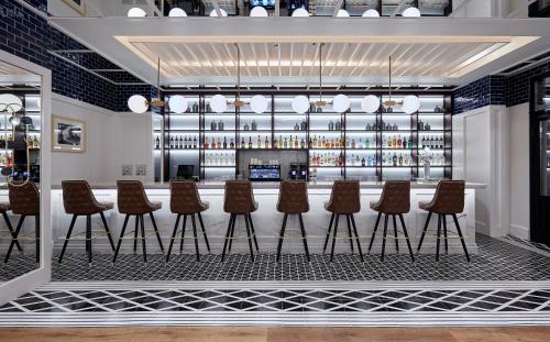 a bar with a row of brown chairs and a counter at Radisson Blu 1882 Hotel, Barcelona Sagrada Familia in Barcelona