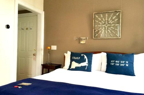 a bedroom with a bed with blue and white pillows at Benchmark Inn in Provincetown