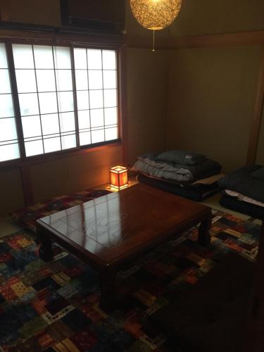 a living room with a coffee table and a bed at Guest house daisho oshiro asobi in Matsue