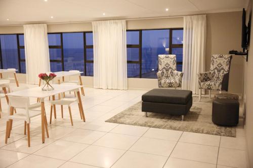 a living room with a table and chairs and windows at Eden Guesthouse B&B in Dana Bay