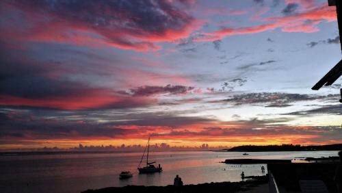 a sunset with a sail boat in the water at Blue Beryl Guest House in Blue Bay