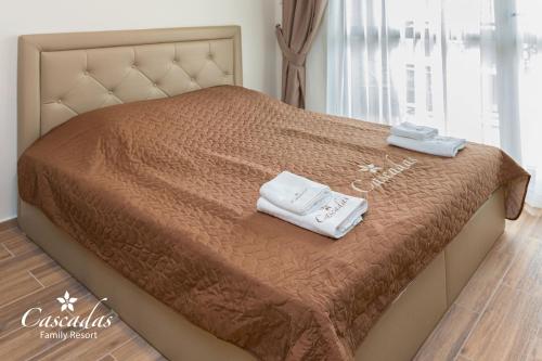 a bed with two towels sitting on top of it at Cascadas Family Resort in Sunny Beach