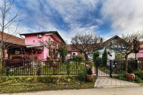 a pink house with a fence in front of it at Biser apartmani in Vrdnik