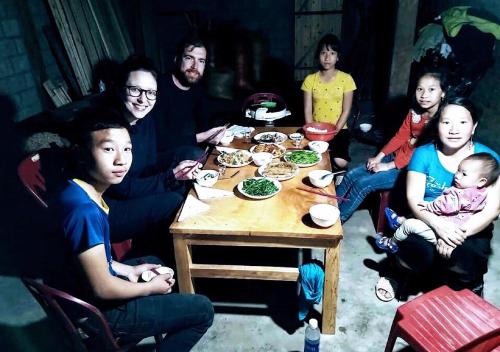 Un groupe de personnes assises autour d'une table et mangeant de la nourriture dans l'établissement Sapa Hmong Bungalow Homestay, à Sa Pa
