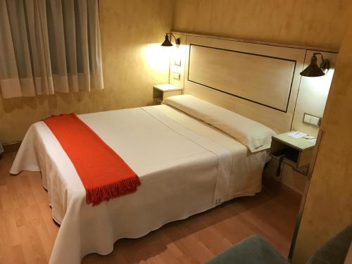a bedroom with a large white bed with a red blanket at Hotel Castillo de Javier in Pamplona