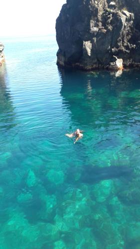 a person swimming in the water near some rocks at Azores Hibiscus House - Mountain and Sea in São Roque do Pico
