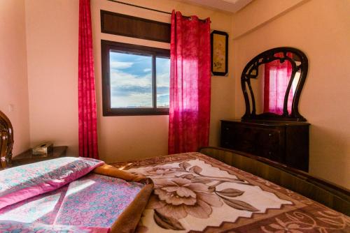 a bedroom with a bed with pink curtains and a window at Résidence Bab El Janoub in Ouarzazate