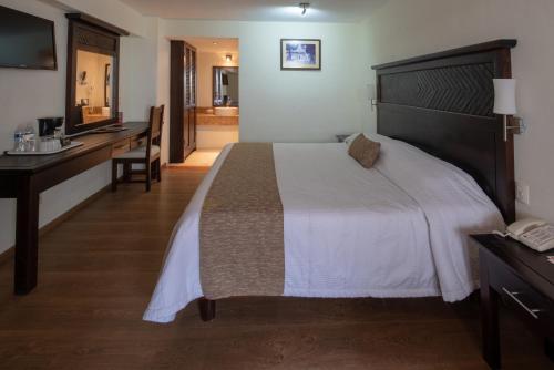a hotel room with a large bed and a desk at Plaza Magnolias in San Cristóbal de Las Casas