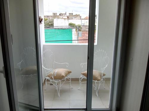 Blick auf einen Balkon mit Stühlen und einem Fenster in der Unterkunft DTO SERRANO in Tandil