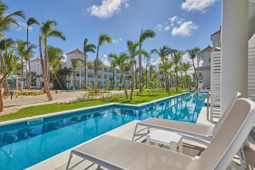 a view of the pool at the resort with chairs and palm trees at Bahia Principe Luxury Ambar - Adults Only All Inclusive in Punta Cana