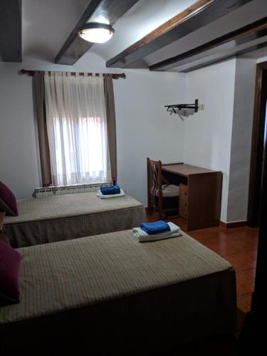 a room with three beds and a desk and a window at La Barbacana in Tramacastiel