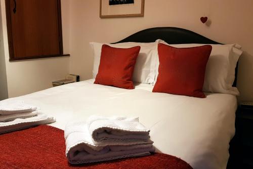 a bed with white sheets and red pillows on it at Dove Cottage, Tideswell in Tideswell