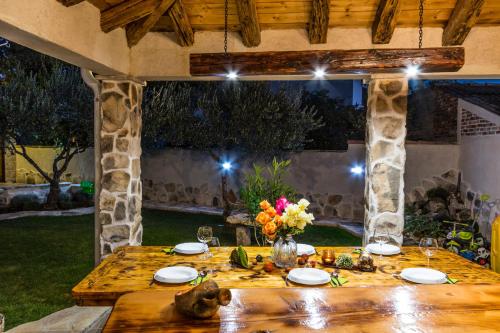 a wooden table with plates and flowers on it at Villa Andrija in Šibenik