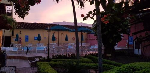 a patio with tables and umbrellas in front of a building at Casa Hotel Guaracú in Santa Fe de Antioquia