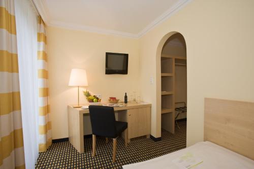 a hotel room with a desk and a chair at relexa hotel Schatten Stuttgart in Stuttgart