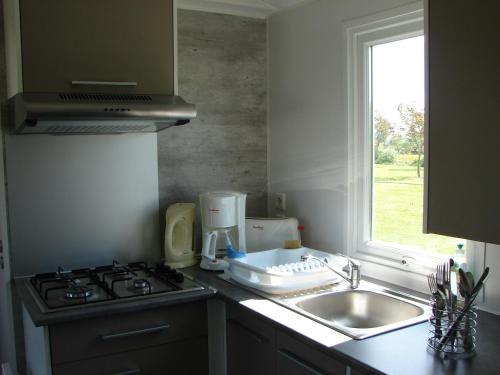 een keuken met een wastafel, een fornuis en een raam bij Camping Moulin de Collonge in Saint-Boil