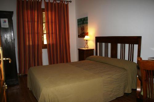 1 dormitorio con cama, cortinas de color naranja y ventana en CASA RURAL PARAJE LUCO en Quinto