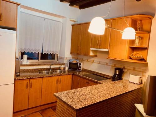 a kitchen with wooden cabinets and a counter top at Casa Rural el Comercio Sierra de Francia in San Miguel de Valero