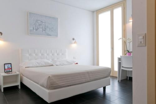 a white bedroom with a white bed and a desk at 6 Porte Guesthouse in Mantova