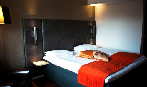 a bedroom with a bed with an orange blanket at Comfort Hotel Park in Trondheim