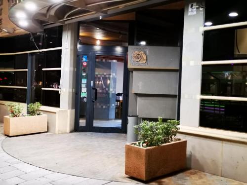 a building with two potted plants in front of it at HR Hotel in Monfalcone