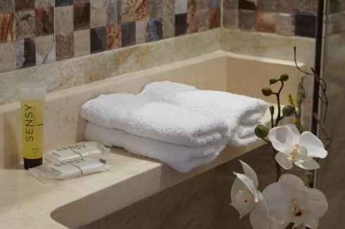 Baño con toallas en una encimera con flores en ARI Hotel, en Cali
