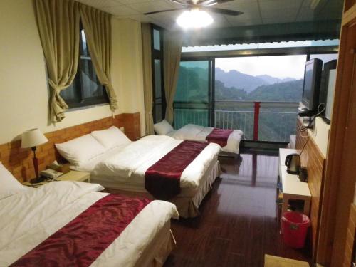 a hotel room with three beds and a large window at King Villa in Heping