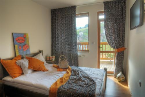 1 dormitorio con 1 cama con almohadas de color naranja y ventana en The Poppies House, en Progled