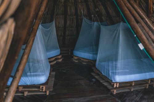 a room with two blue seats in a thatch roof at Los Hermanos Beach Hostal in Guachaca