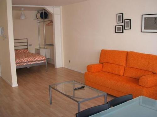 a living room with an orange couch and a glass table at Apartamentos Loft Tarifa in Tarifa