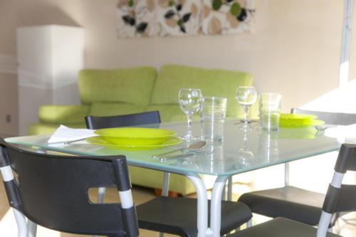 mesa de comedor con gafas y sofá verde en Apartamentos Loft Tarifa, en Tarifa