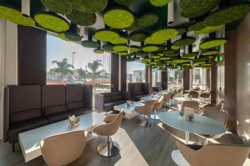 a waiting room with tables and chairs and large windows at 8Piuhotel in Lecce