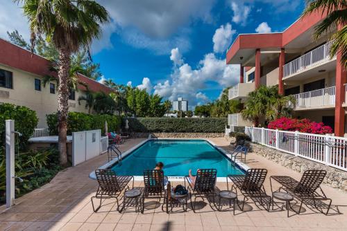 a person sitting in chairs next to a swimming pool at La Costa Beach Club in Pompano Beach