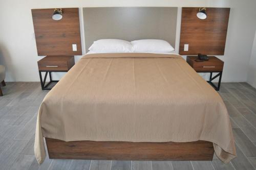 ein Schlafzimmer mit einem großen Bett mit zwei Nachttischen in der Unterkunft Hotel El Sausalito in Ensenada