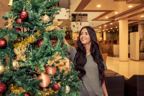 a woman is standing next to a christmas tree at Matsubara Acqua Park Hotel in Maceió