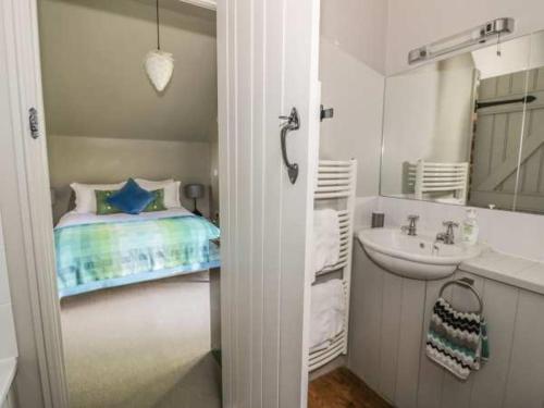 a small bathroom with a bed and a sink at Carp's Rise Cottage in Somerford Keynes