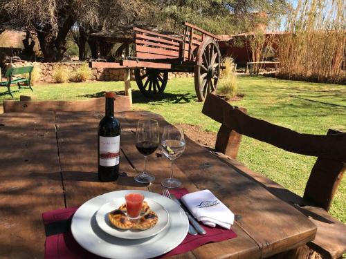 a table with a plate of food and a bottle of wine at La Casa De La Bodega - Wine Boutique Hotel in Cafayate