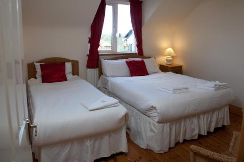 two twin beds in a room with a window at Ceol na Mara Holiday Homes - Cois Tra & Cor na dTonn in Enniscrone