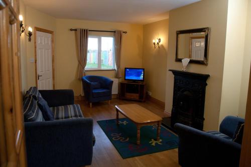 a living room with blue chairs and a television at Ceol na Mara Holiday Homes - Cois Tra & Cor na dTonn in Enniscrone
