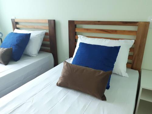 a bedroom with two beds with blue and white pillows at Beira Mar Village in Pinheira