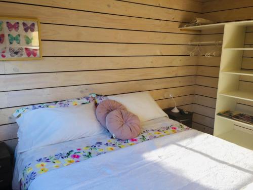 a bed in a room with a wooden wall at Cabaña del Bosque in Pichilemu