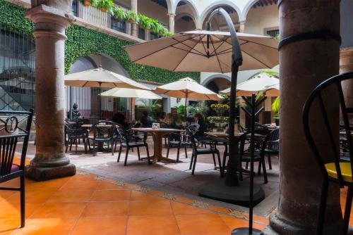 an outdoor patio with tables and chairs and umbrellas at Hotel Hidalgo in Querétaro