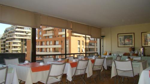 Un comedor con mesas y sillas blancas. en Alessandria Apart - El Bosque Norte, en Santiago