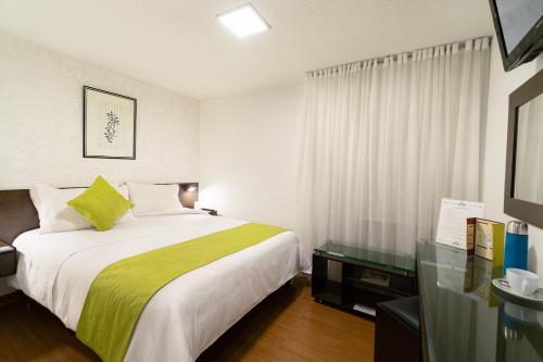 a bedroom with a bed with a green blanket at Hotel Don Saul in Pasto