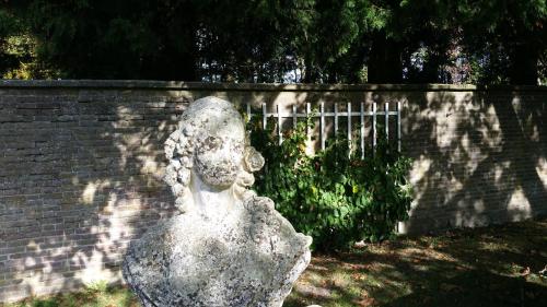 una estatua de una mujer sentada junto a una pared de ladrillos en B&B en SPA Landgoed Matanze, en Terwolde