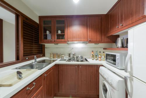 a kitchen with wooden cabinets and a sink and a dishwasher at Centre Point Sukhumvit Thong-Lo in Bangkok