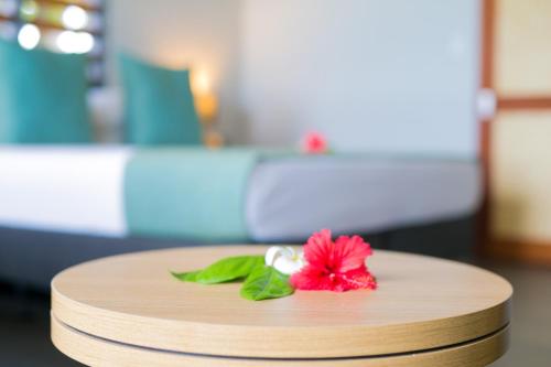 a red flower sitting on top of a wooden table at Serenity Island Resort in Mamanuca Islands