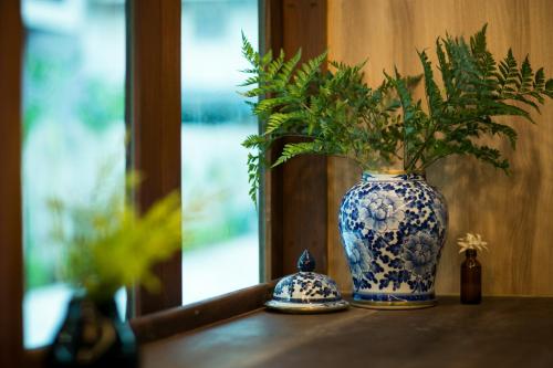 a blue and white vase with a plant on a table at DeeProm Pattaya Hotel in Pattaya Central