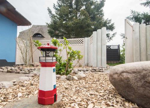 a red and white lighthouse in front of a fence at K03 Fischerkaten MARET max 4 Pers in Dorf Körkwitz