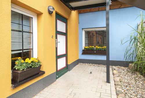um edifício amarelo com duas janelas e uma porta com flores em K04 Fischerkaten MELINA max 2 Pers em Dorf Körkwitz